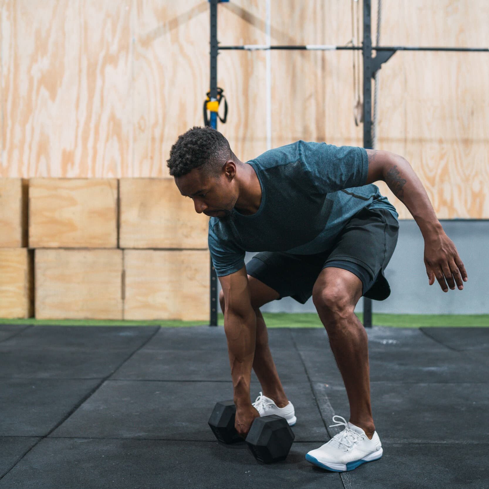 Portrait of young crossfit athlete doing exercise with dumbbell at the gym. Crossfit, sport and healthy lifestyle concept.